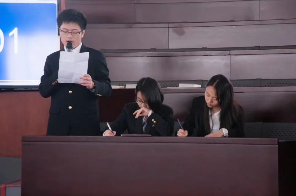 Zijiang speaking into a microphone alongside teammates at an English debate competition